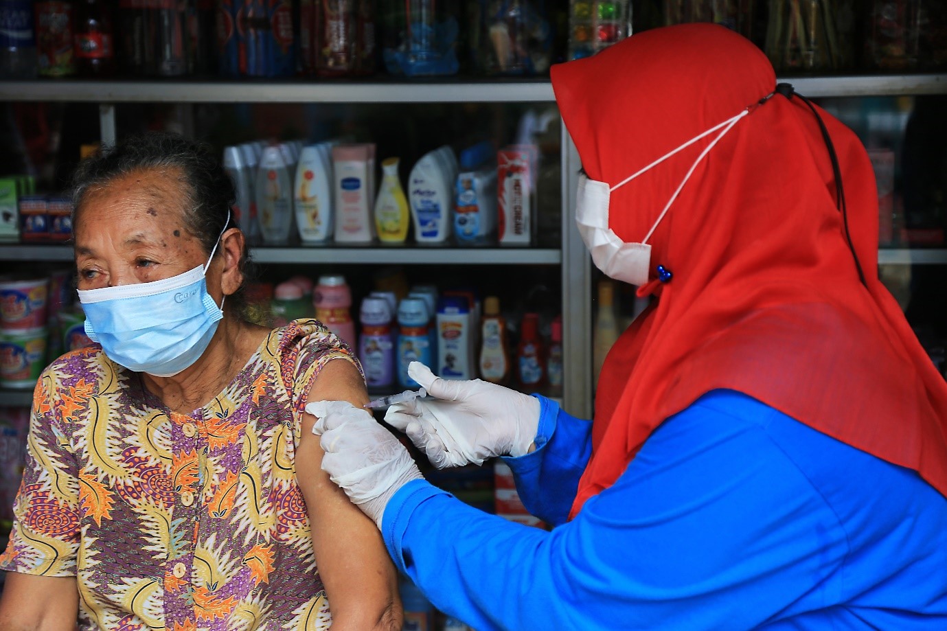 Mbak Mintasih, a resident of Purwokerto Village, receives a COVID-19 vaccination in front of her house from a health worker from the Tayu 2 Health Center (photo by: AIHSP Documentation Team)